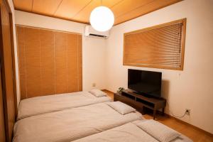 two beds in a room with a tv and a window at Max13ppl Family-Friendly , 110sqm , SpaciousLiving&4BRM , LongStay OK , 2CarPark , 25min to NAGOYA & LEGO & Outlet in Yatomi 