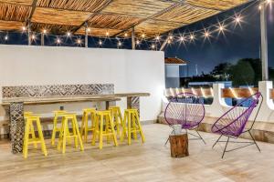 a patio with yellow and purple chairs and a table at Valentina Suites by Las Flores Vacation Rentals in Playa del Carmen