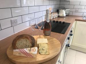 a bottle of wine and a plate of cheese and wine glasses at Clock Tower Cottage in Whitchurch