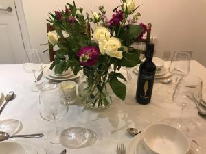 a table with a vase of flowers and a bottle of wine at Clock Tower Cottage in Whitchurch +13 photos
