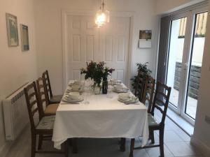 a dining room table with a white table cloth and chairs at Clock Tower Cottage in Whitchurch