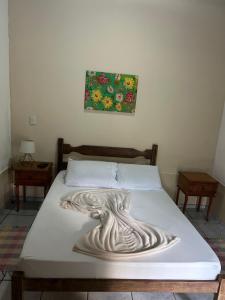a bed in a bedroom with a painting on the wall at Pousada céu azul Paraty in Paraty