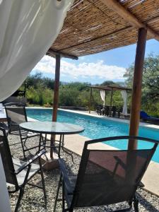 a table and chairs next to a swimming pool at CABAÑAS ALMA SERENA in Capilla del Monte