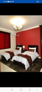 a bedroom with three beds and a red wall at فندق دير البتراء السياحي in Wadi Musa