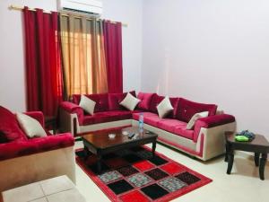 a living room with red couches and a coffee table at فندق دير البتراء السياحي in Wadi Musa