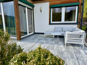 a patio with a couch and chairs and windows at Gipfelruhe-ganzes Ferienhaus mit Sauna, Garten & Spielzimmer- Ramsau am Dachstein in Ramsau am Dachstein