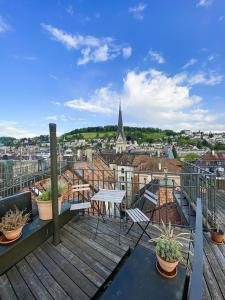a balcony with a table and chairs and a view of a city at Zentrales Design Loft über den Dächern St Gallens in St. Gallen