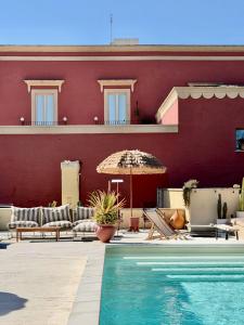 a building with a swimming pool and an umbrella at Antica Masseria le Monache in Grottaglie