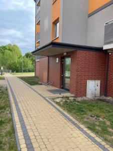 a brick building with a brick sidewalk in front of it at Apartament pod dębami in Trzcianka