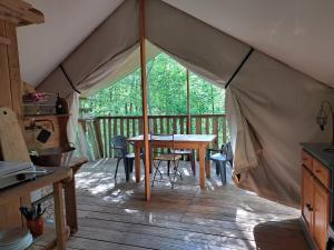a tent with a table and chairs on a deck at Camping Terre Rouge in Villecomtal