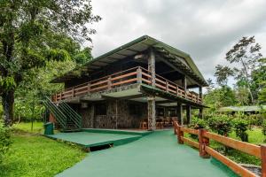 a house with a balcony and a green floor at Chalets Silencio del Bosque in Fortuna
