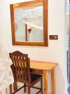 a wooden table with a mirror and a wooden chair at Beach Wave Hotel in Arugam Bay
