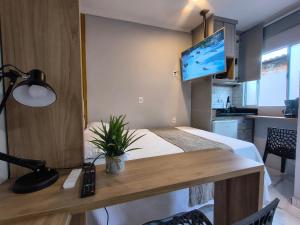 a room with a bed and a desk with a television at Lofts Sky Life in São José dos Campos