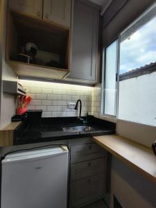 a kitchen with a sink and a white refrigerator at Lofts Sky Life in São José dos Campos