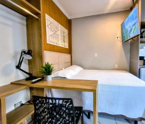 a small room with a bed and a desk with a table at Lofts Sky Life in São José dos Campos