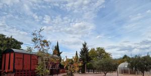 a red building and a church with a cloudy sky at Vagón con sesión de Jacuzzi in Caravaca de la Cruz