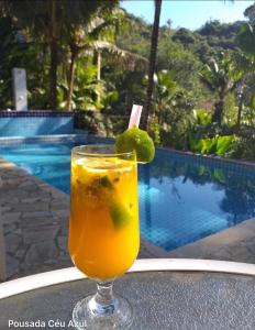 a drink sitting on a table next to a pool at Pousada céu azul Paraty in Paraty