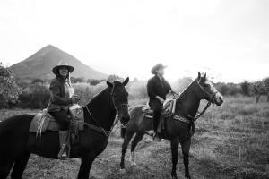 a man and a woman sitting on horses in a field at Horse & Bed Hostel in Puebla