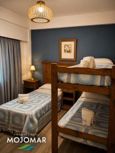 a bedroom with two bunk beds and a blue wall at Mojomar Pinamar Hotel in Pinamar