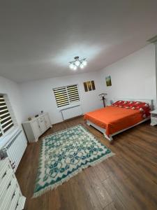 a bedroom with an orange bed and a rug at La Paramon ! in Sângeorz-Băi +11 photos