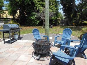 three blue chairs and a grill in a yard at Indian Beach Cottage in Sarasota