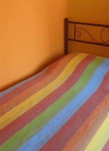 a bed with a multicolored striped comforter on it at Angela's House in Barga