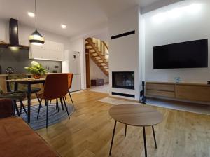 a living room with a table and a living room with a tv at W Sosnowym Lesie Pluski in Pluski