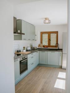 a kitchen with blue cabinets and white appliances at Hiša Potoki in Kobarid