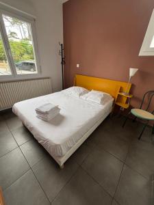 a bedroom with a bed with white sheets and a window at Le Moutchico in Lacanau