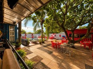 a patio with red tables and chairs and trees at Tetris in Foz do Iguaçu