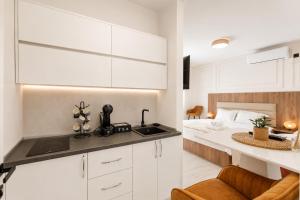 a kitchen with white cabinets and a bed in a room at Apartmani Centar in Igalo +14 photos