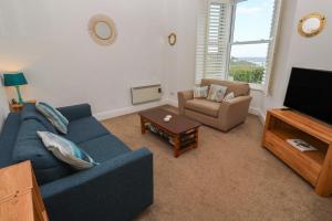 a living room with a blue couch and a tv at Apartment 1 Llewellan in Carbis Bay