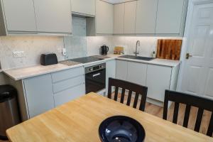 a kitchen with white cabinets and a wooden table at Apartment 1 Llewellan in Carbis Bay +9 photos