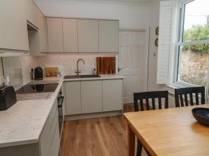 a kitchen with white cabinets and a wooden table at Apartment 1 Llewellan in Carbis Bay