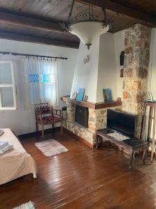a living room with a stone fireplace and a couch at Aiolos in Skala