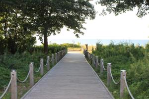 a wooden walkway with rope barriers leading to a beach at Seegurke in Am Schwarzen Busch +5 photos