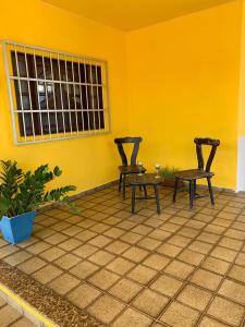 Zwei Stühle und ein Tisch in einem Raum mit gelber Wand in der Unterkunft Oasis Maceio in Maceió