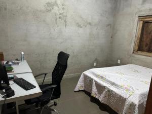 a room with a desk with a computer and a bed at Chácara do Waltinho in Contagem