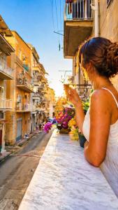 a woman sitting on a ledge looking at a street at Almantra Rooms - Valle dei Templi e Mare in Favara +39 photos