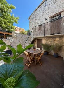 eine Terrasse mit einem Holztisch und Stühlen neben einem Gebäude in der Unterkunft Lézardéchois in Saint-Martin-dʼArdèche