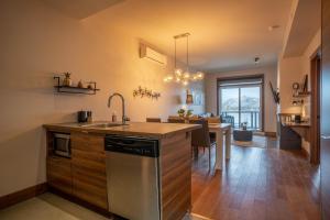a kitchen with a sink and a dining room at Condo overlooking Lac Superieur & mountain views in Lac-Superieur +36 photos