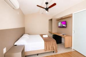 a bedroom with a bed and a flat screen tv at Vila da Praça Pousada in Capitólio