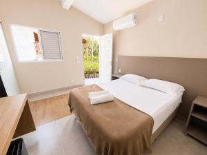 a bedroom with a bed and a desk and a window at Vila da Praça Pousada in Capitólio