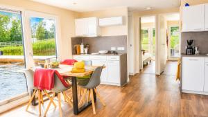 a kitchen with white cabinets and a table and chairs at Floatinghouse Milan - LP9 in Vetschau