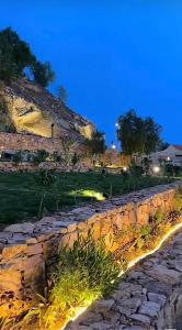 a stone wall with lights on it at night at شاليهات الحدبان - Al Hadban Chalets in Ash Shafa