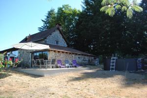 a group of chairs and an umbrella in front of a building at Lakeview Family Fishing Gite in Roussines