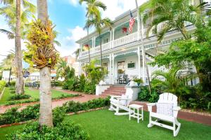 an exterior view of a building with white chairs and palm trees at Southernmost Point Guest House & Garden Bar in Key West