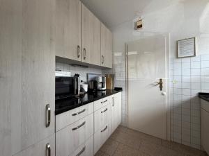 a kitchen with white cabinets and a white refrigerator at Casa Calvin in Unteruhldingen