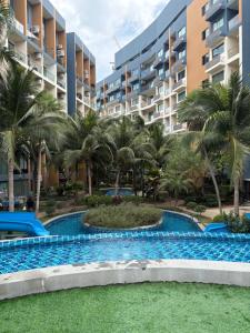 a swimming pool in front of a building with palm trees at Laguna Beach Resort 2 Pattaya in Jomtien Beach