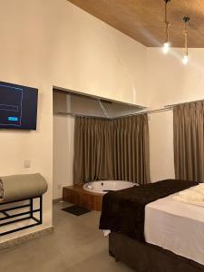 a bedroom with a bed and a tub and a television at CORAÇÃO DO ALTO CHALES Hidromassagem in Caparaó Velho